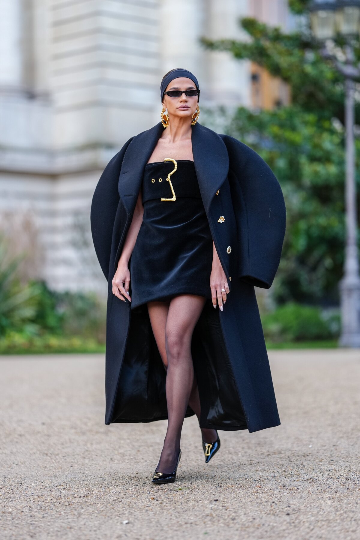Párizs, Franciaország - JANUÁR 27.: Thassia Naves fekete fejpántot, fekete napszemüveget, arany Schiaparelli fülbevalót, fekete oversized Schiaparelli kabátot, fényes fekete pánt nélküli, övvel díszített, fekete szatén szatén miniruhát, fekete átlátszó hálós harisnyát, fényes fekete hegyes orrú, Schiaparelli kulcslyukas bőrcipőt visel a Schiaparelli külső helyszínen, a 2025-ös tavaszi/nyári Haute Couture bemutatóján, Párizsban, Franciaországban, 2025. január 27-én. (Fotó: )