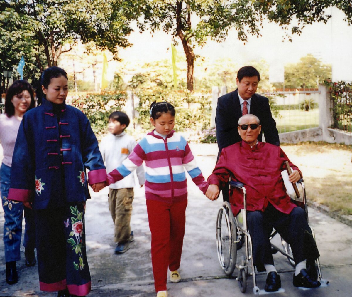 Xi tolja az apját, miközben feleségével és lányával, Xi Mingze-vel sétál 2012-ben.